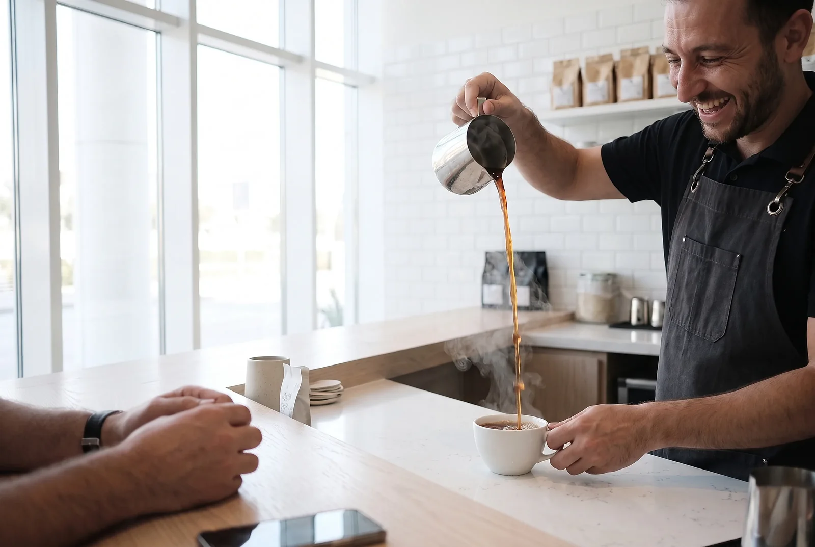 A barista pouring karak at a cafe counter